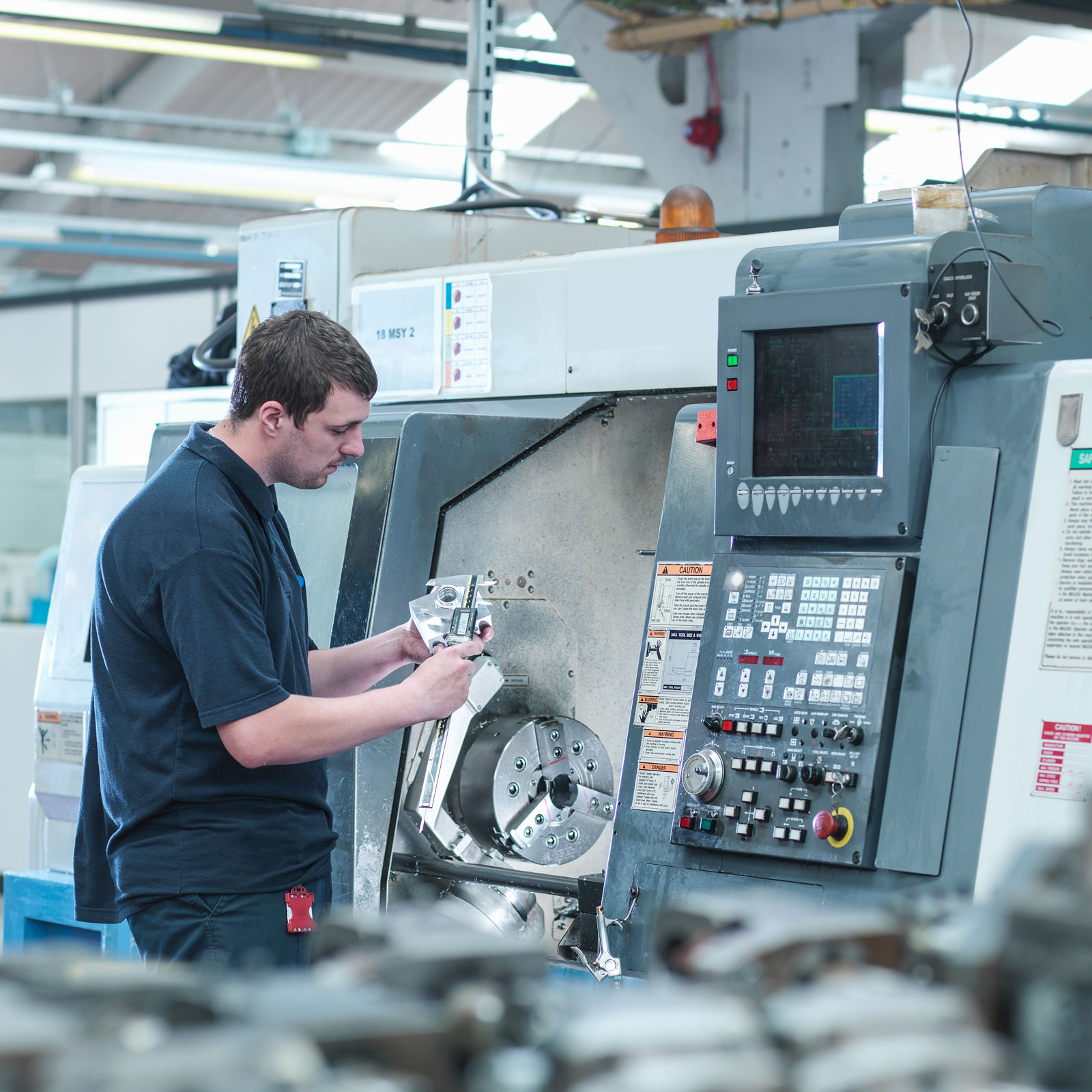 Man holds CNC lathe: DNC and CMMS software